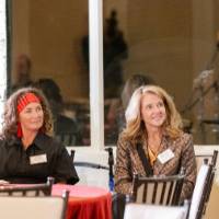 Two woman at reception smiling and looking up at speaker